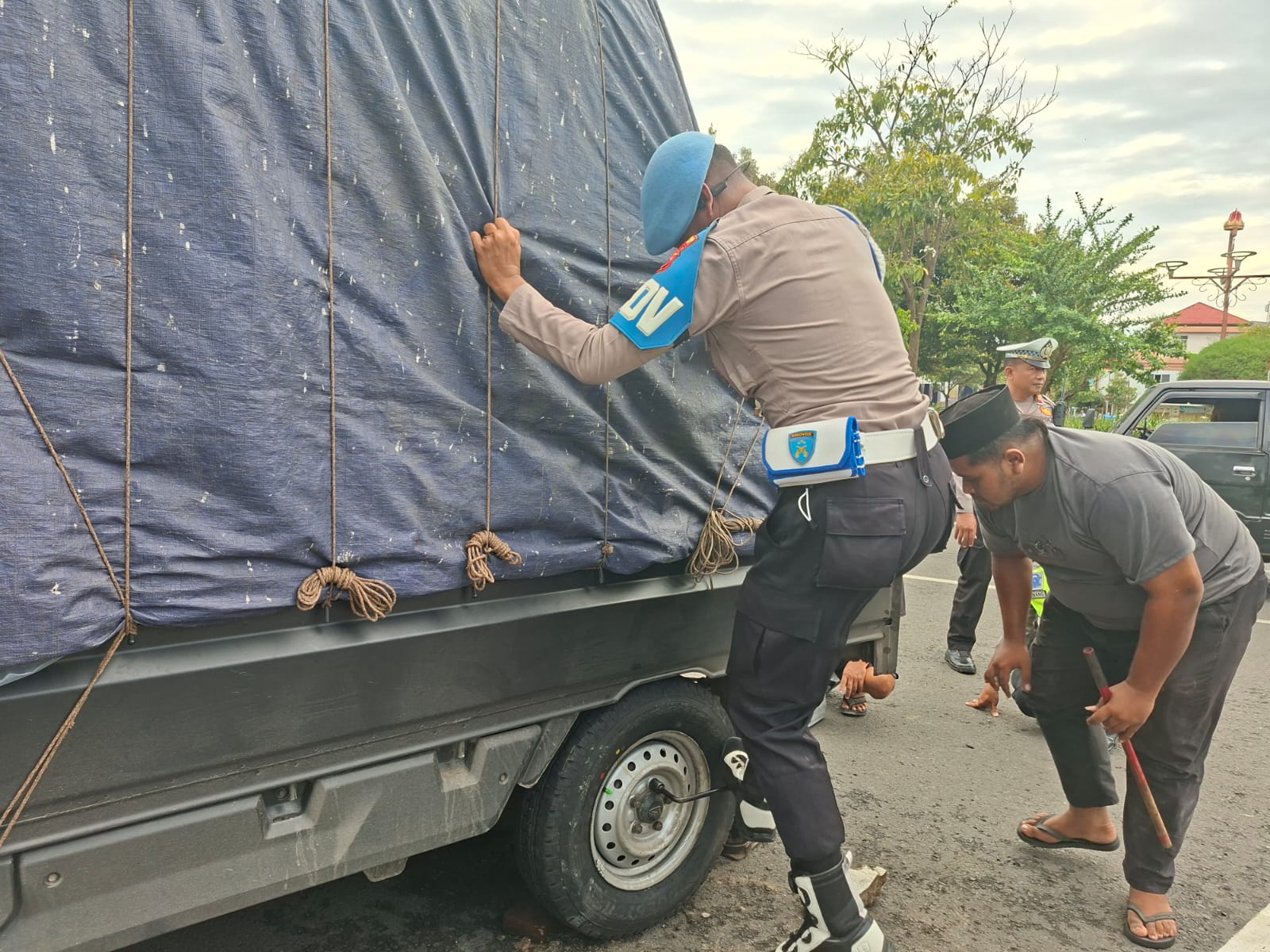 Seorang anggota Polresta Pati membantu warga yang mengalami pecah ban mobil di sekitar Alun - Alun Pati. (ACHMAD ULIL ALBAB/RADAR PATI)