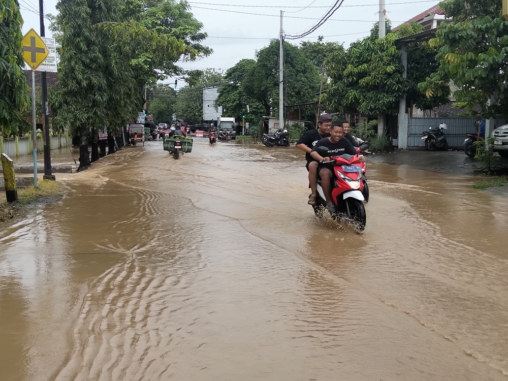 TERGENANG: Warga melintasi genangan air di wilayah Pati Kota belum lama ini. (ANDRE FAIDHIL FALAH/RADAR KUDUS)