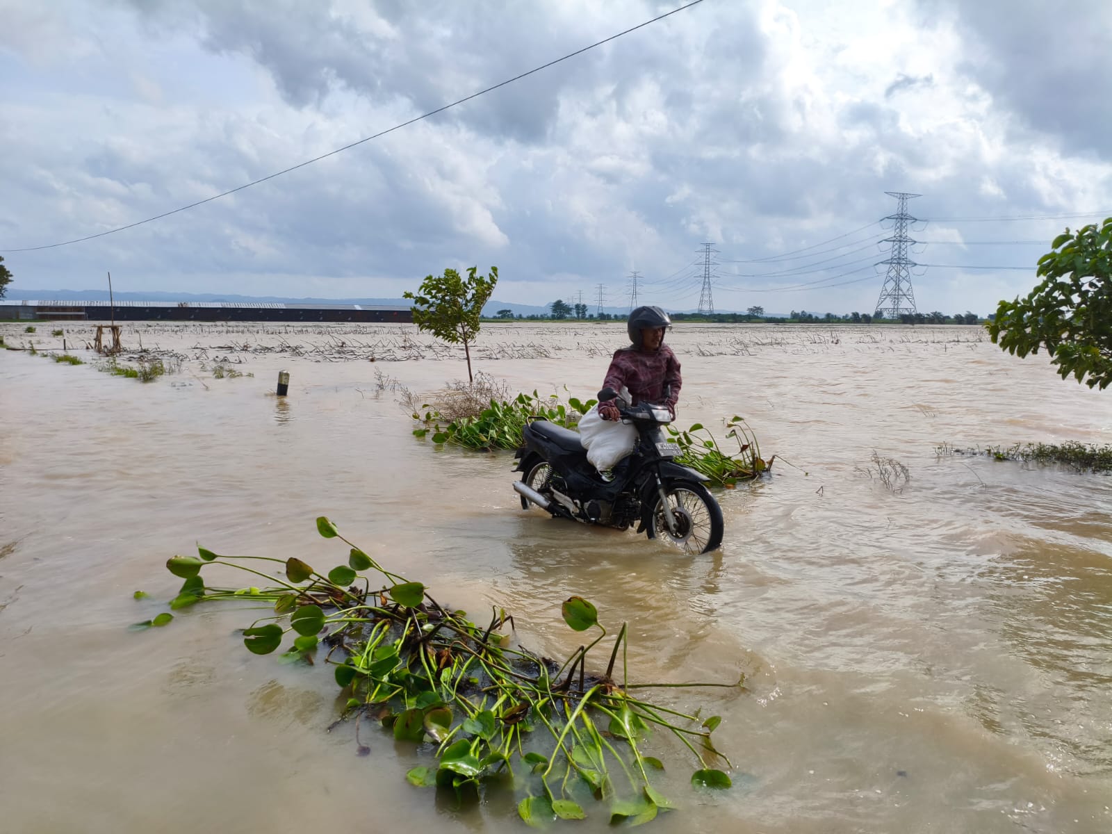 Seorang pengguna jalan mendorong sepeda motor yang mogok usai menerobos banjir di jalur alternatif Kudus - Kayen atau Jalan Kasiyan - Poncomulyo Sukolilo. (ACHMAD ULIL ALBAB/RADAR KUDUS)