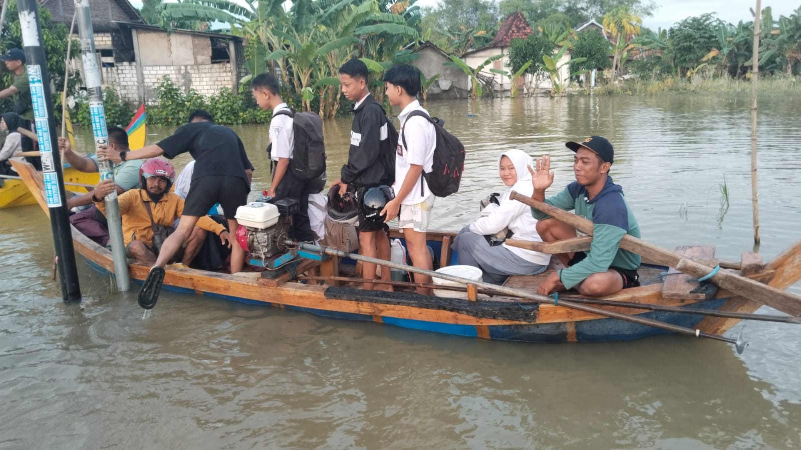 Warga Desa Mintobasuki Kecamatan Gabus Pati diantar menggunakan perahu untuk melintasi pemukiman yang banjir. (PEMDES MINTOBASUKI)