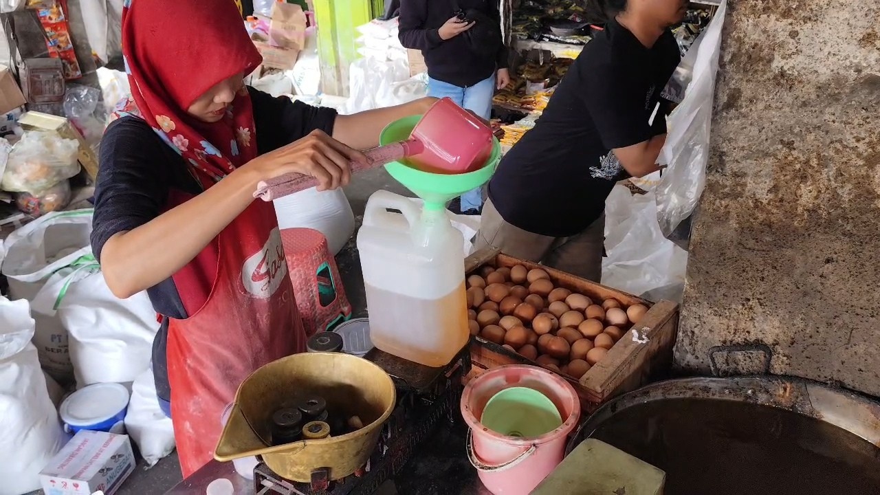 DISUNTAK: Salah satu pedagang menuang minyak goreng ke wadah di salah satu toko di Pati belum lama ini. (ANDRE FAIDHIL FALAH/RADAR PATI)
