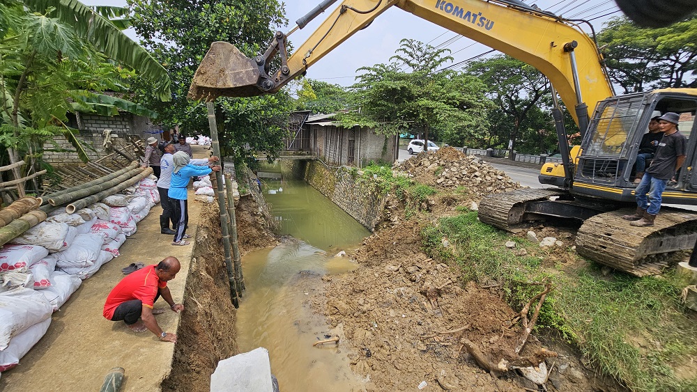 PENGERUKAN: Petugas melakukan pembersihan material yang menyumbat aliran sungai di ruas Jalan Pati&ndash;Juwana. (ANDRE FAIDHIL FALAH/RADAR PATI)