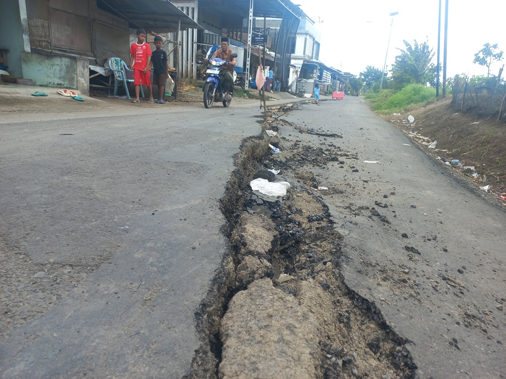 TANAH LABIL: Warga melintas di jalur jalan yang ambles di Desa Guwosoberto, Kecamatan Welahan, Kamis (19/2).