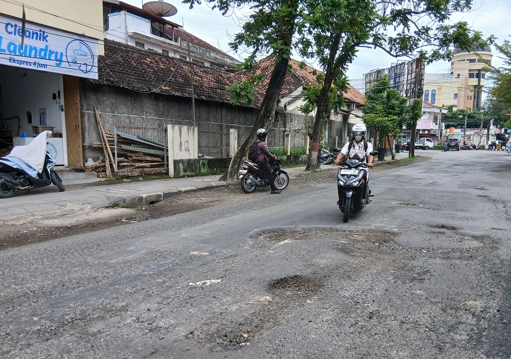 RUSAK: Pengendara memperlambat laju kendaraan saat melintasi Jalan Gunandar karena banyaknya lubang di badan jalan. (EKO SANTOSO/RADAR PATI)