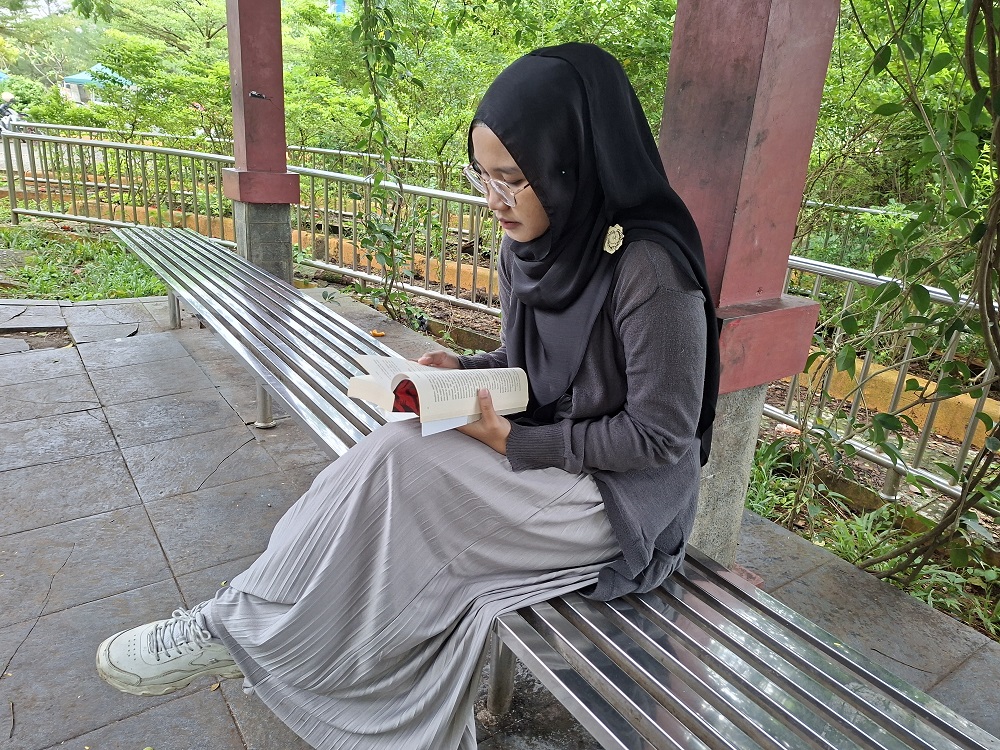 NGABUBURIT: Rofida Ilya menunggu waktu berbuka dengan membaca buku di Balai Jagong Kudus, Jumat (20/2). (ANDIKA TRISNA SAPUTRA/RADAR PATI) 