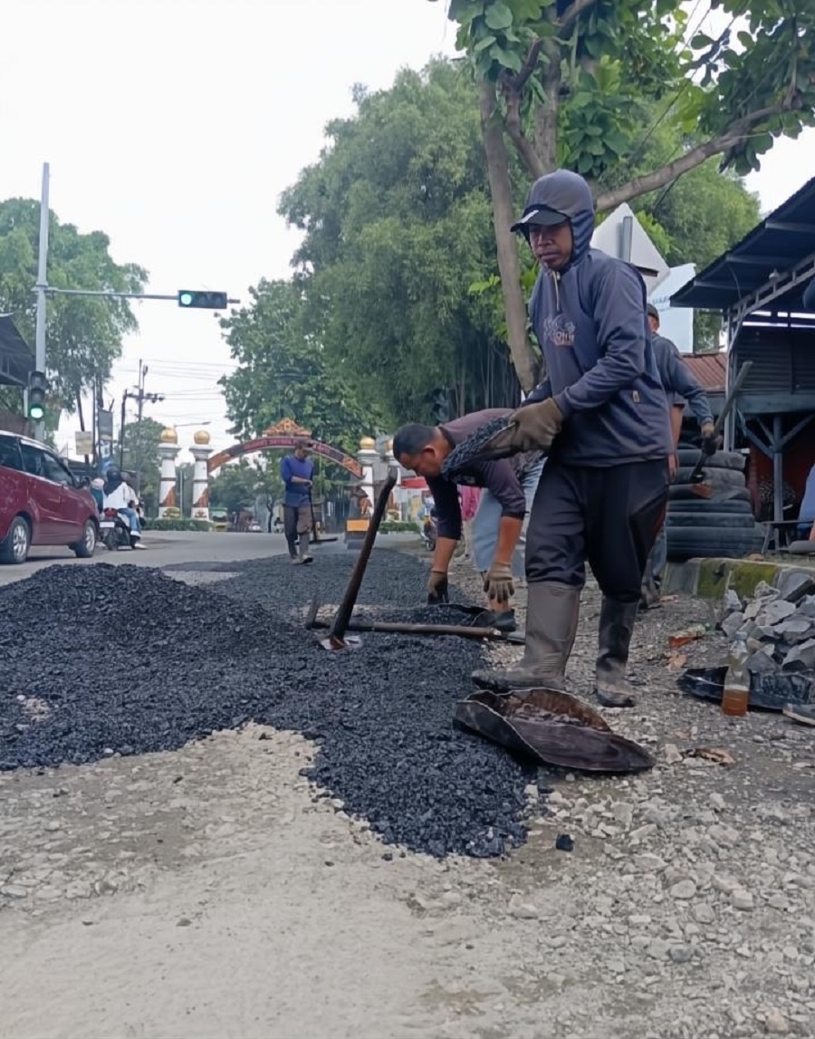 DIPERBAIKI: Pekerja proyek menambal jalan berlubang di jalan Pati-Kayen belum lama ini. (ANDRE FAIDHIL FALAH/RADAR PATI) 