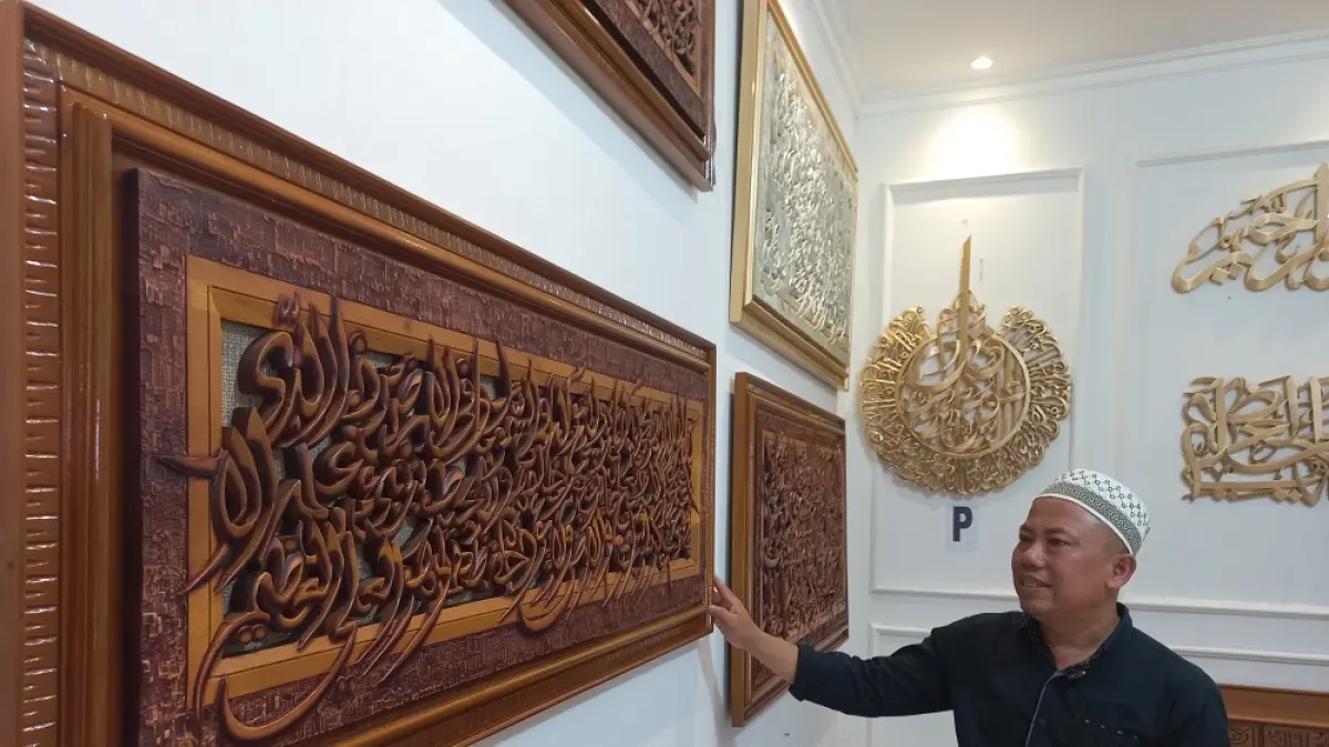 MENAWAN: Norhadi menunjukkan karya kaligrafi di gerai rumah usahanya. (FIKRI THOHARUDIN/RADAR PATI)