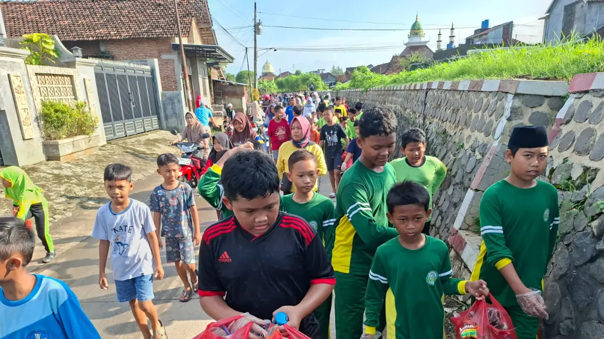 BERSIH-BERSIH: Peserta jalan sehat memungut sampah-sampah yang terdapat di rute yang dilintasi di Desa Kesambi, Minggu (12/4). (ANDIKA TRISNA SAPUTRA/RADAR PATI)