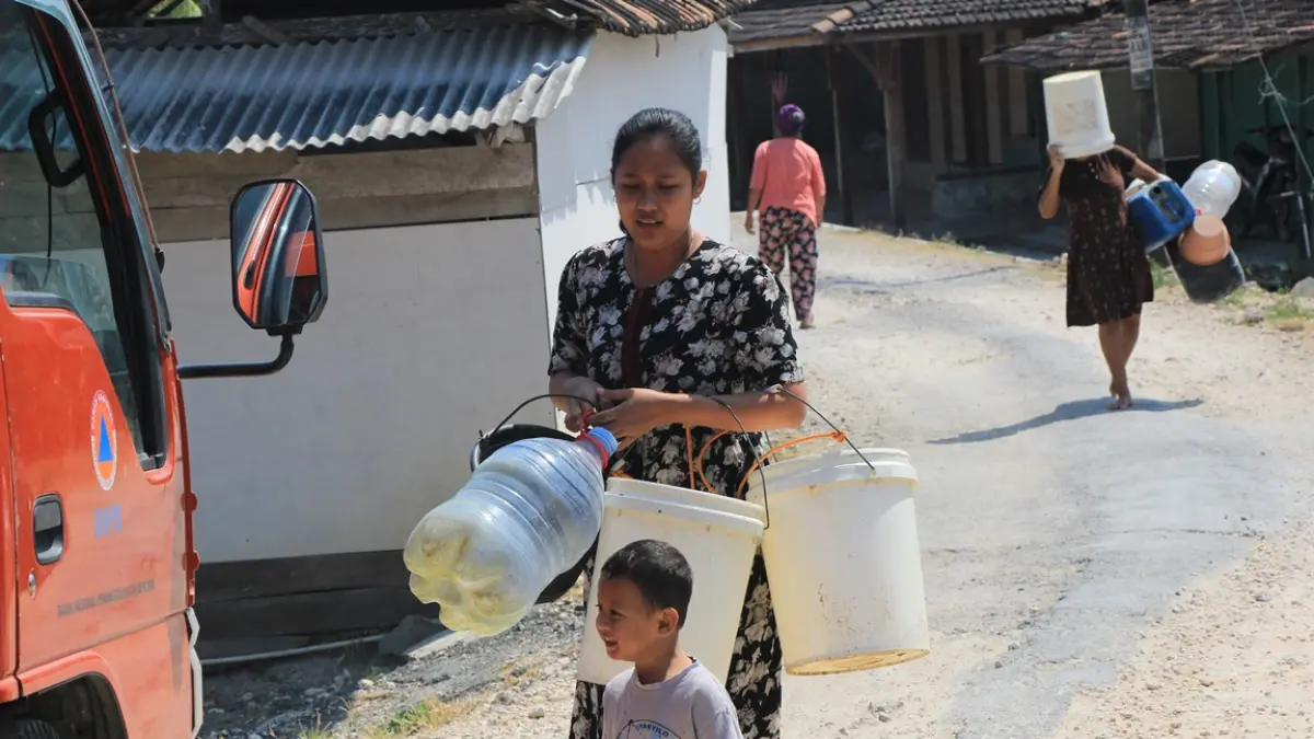 ANCANG-ANCANG: Seorang ibu bersama anaknya ngangsu air bersih saat terima droping dari BPBD Rembang. (WISNU AJI/RADAR PATI)