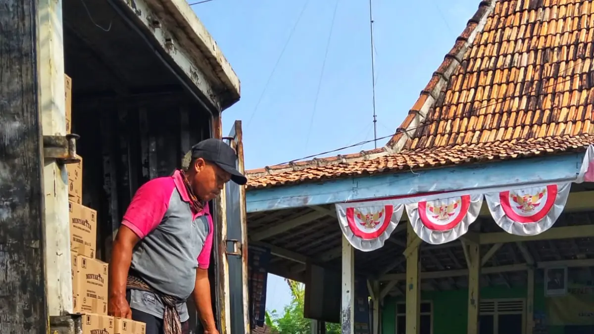 PENYALURAN: Pekerja menurunkan minyak goreng merek MinyaKita untuk bantuan pangan di Desa Pacing, Kecamatan Sedan, Kabupaten Rembang. Minyak goreng yang diduga terkontaminasi solar telah ditarik dan diganti seluruhnya. (BULOG REMBANG UNTUK RADAR PATI)