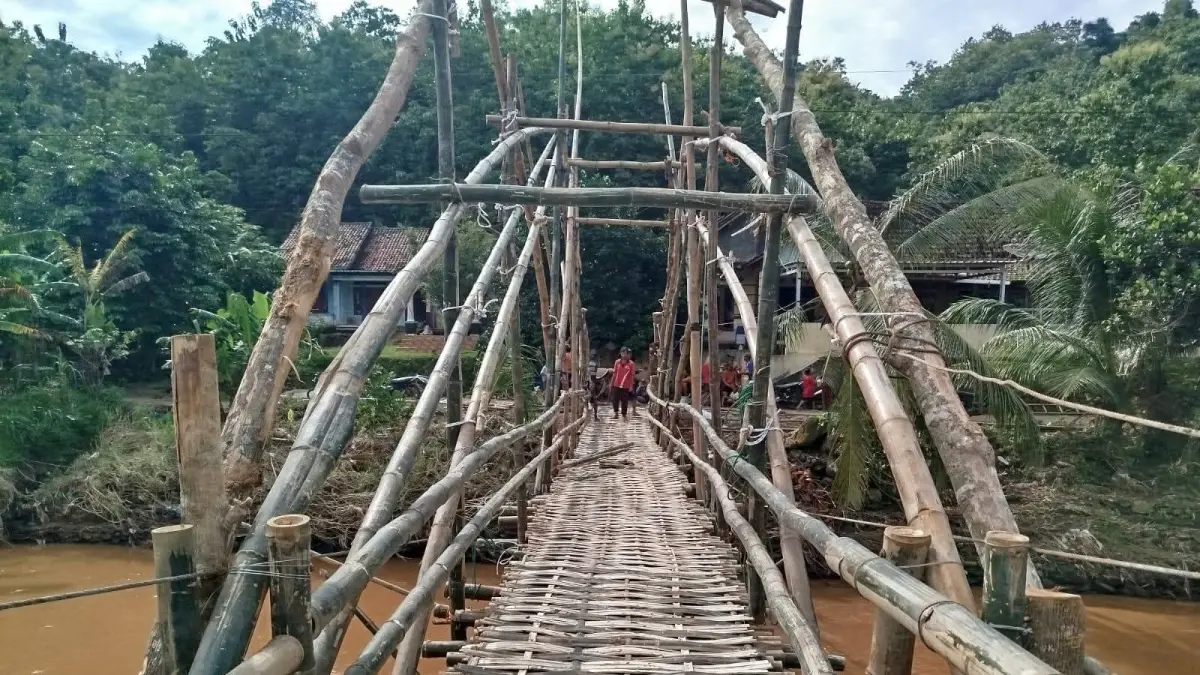 SEGERA DIBANGUN : Seorang Warga Melintasi Jembatan Darurat Setelah Jembatan Itu Rusak Akibat Banjir. Rencananya Jembatan Lendoh akan Dibangun Mulai September Ini (ISTIMEWA)