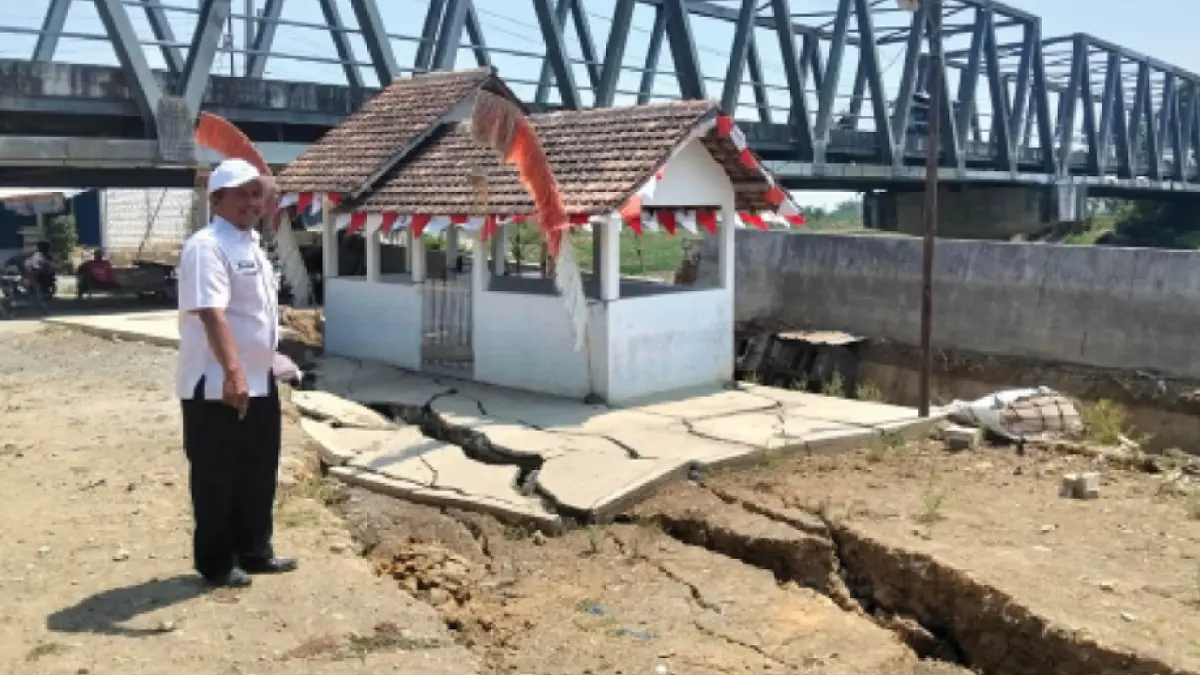 AMBLES: Sekdes Tondomulyo, Jakenan Suhali menunjukkan lokasi retakan sempadan tanah di bawah Jembatan Sampang, (26/8). ANDRE F/RADAR PATI)