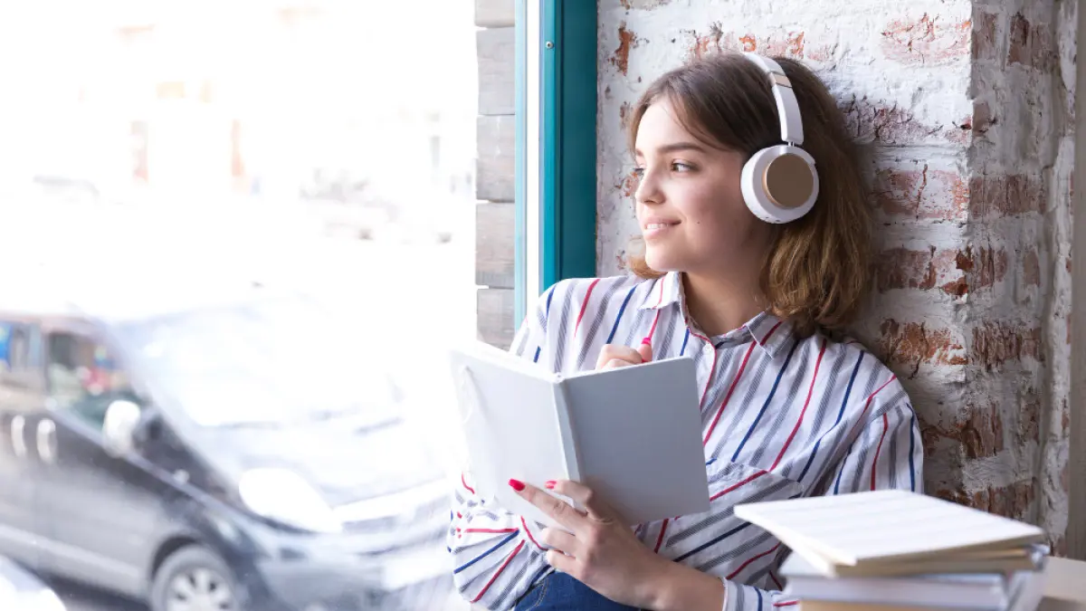 Pembaca menikmati musik sambil membaca buku di waktu santai.