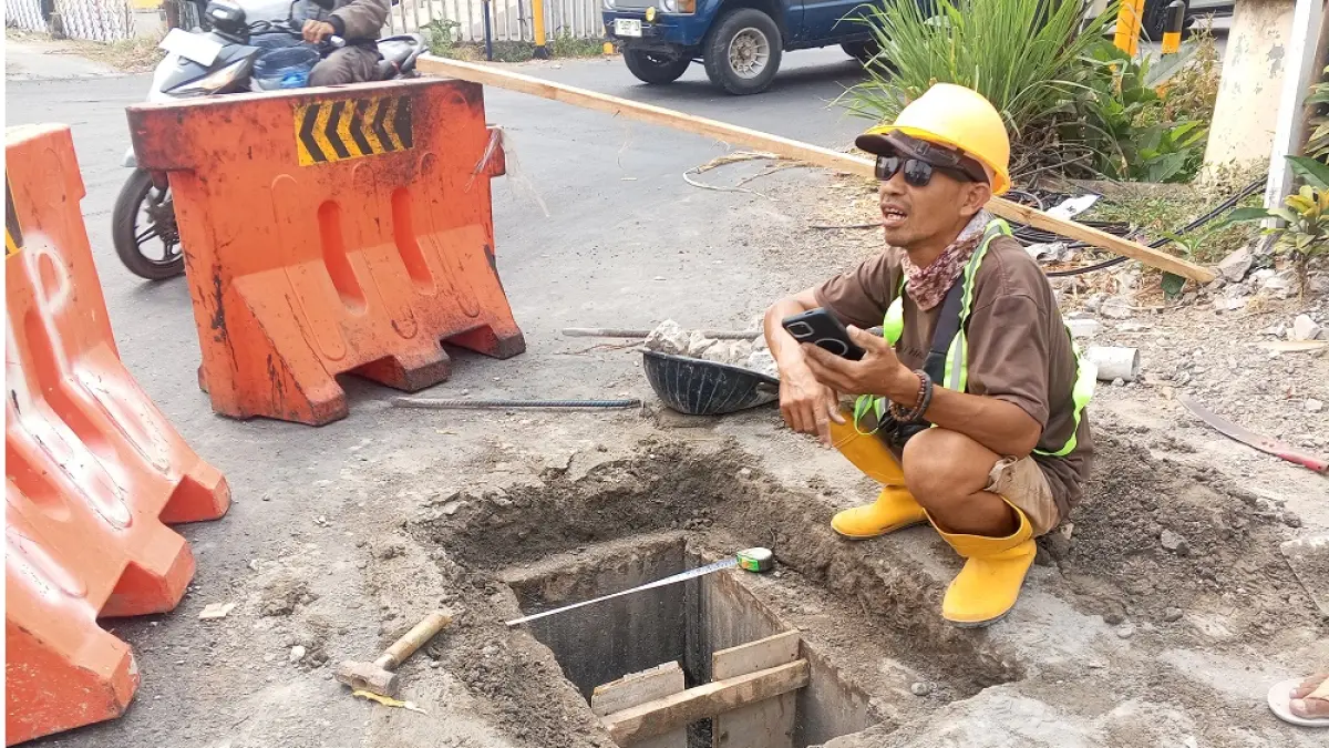 LUBANG: Para pekerja lakukan perbaikan pada drainase jalan yang sempat terbuka pada Jum