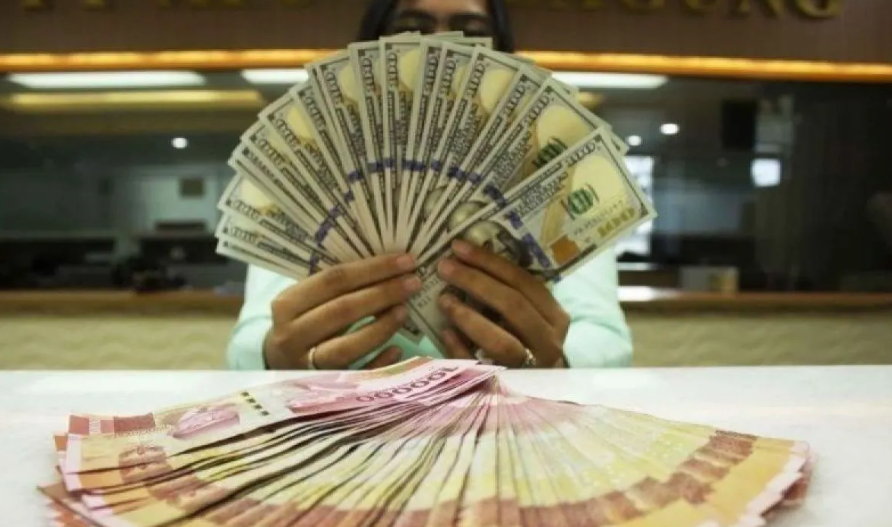 Teller memegang mata uang Dolar AS dan Rupiah di sebuah tempat penukaran uang, Jakarta. (Foto: antara.com)