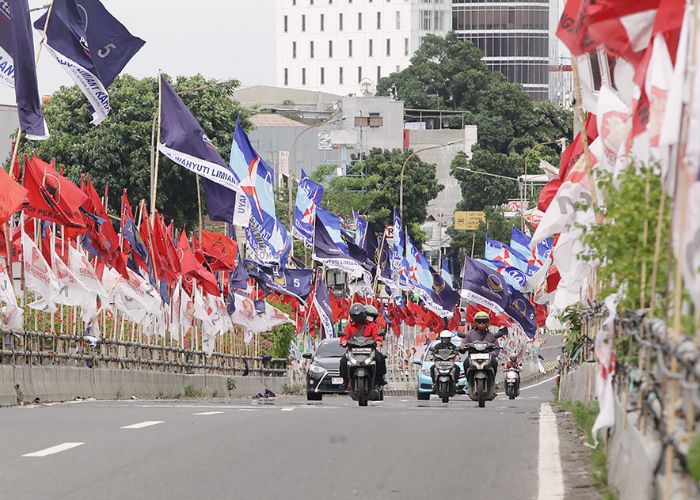 Keberadaan deretan bendera partai politik menimbulkan potensi bahaya bagi pengendara motor di flyover Matraman, Jakarta.