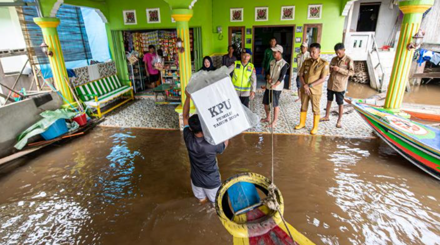 Petugas memanggul kotak suara berisi logistik Pemilu 2024 menuju tempat pemungutan suara di daerah perairan sungai Musi Pulo. (Foto: tempo.co)