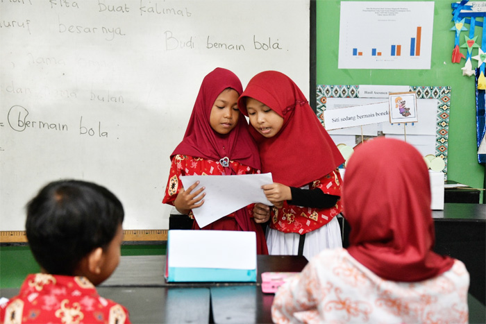 Ilustrasi siswa Sekolah Dasar maju  menjelaskan pekerjaannya kepada siswa lainnya. Kurikulum Merdeka jadi alat bantu peserta didik berkembang sesuai dengan fitrah serta potensinya.