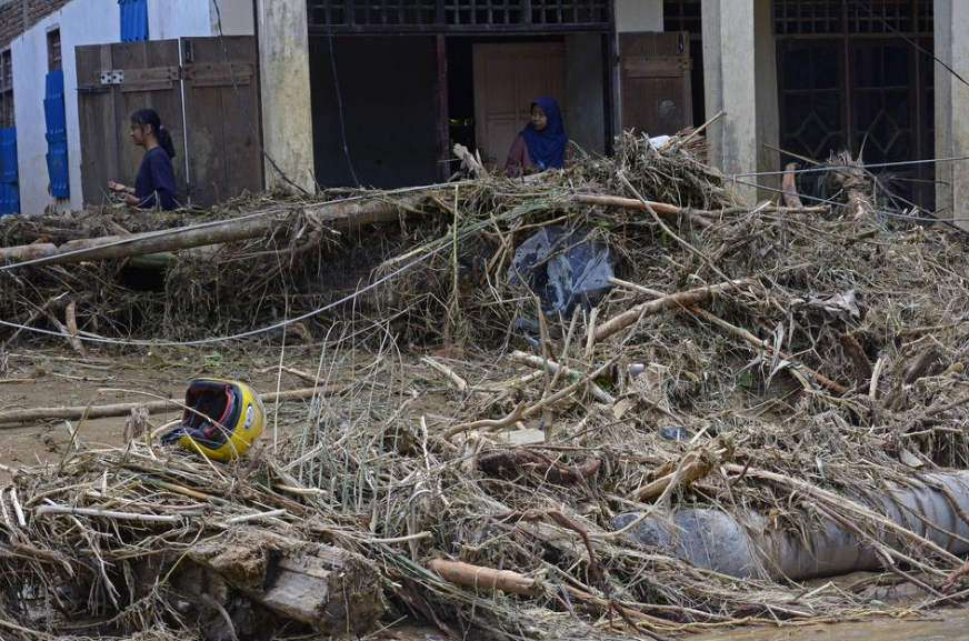 Warga melintas di depan rumah yang terdampak banjir bandang di Desa Kaili, Kecamatan Suli Barat, Kabupaten Luwu, Sulawesi Selatan, Minggu (5/5/2024).