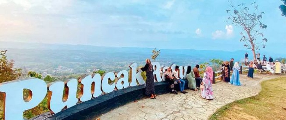 SPOT ANDALAN: Wisatawan berfoto di papan nama Puncak Ratu Pamekasan yang ditempatkan di salah satu sudut bibir bukit. (FOTO: MOCH. IQBAL AFGANI)