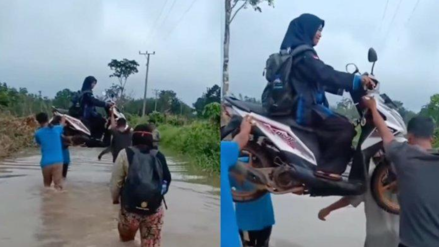 Seorang guru SD di Banyuasin terpaksa digotong bersama motornya untuk melewati jalan digenangi air demi berangkat ke sekolah.