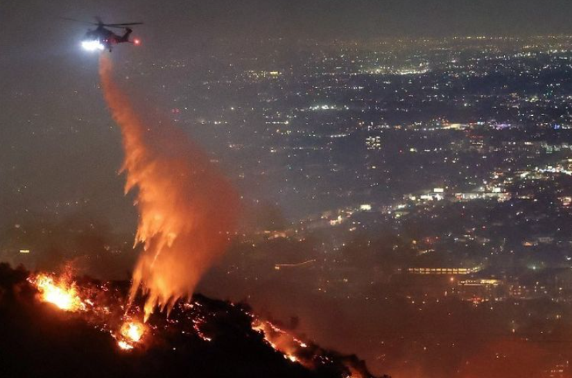 Helikopter menyemprotkan air untuk memadamkan kebakaran hutan Los Angeles atau Sunset Fire di Hollywood Hills, Negara Bagian California, Amerika Serikat, Rabu (8/1/2025).(GETTY IMAGES NORTH AMERICA/MA