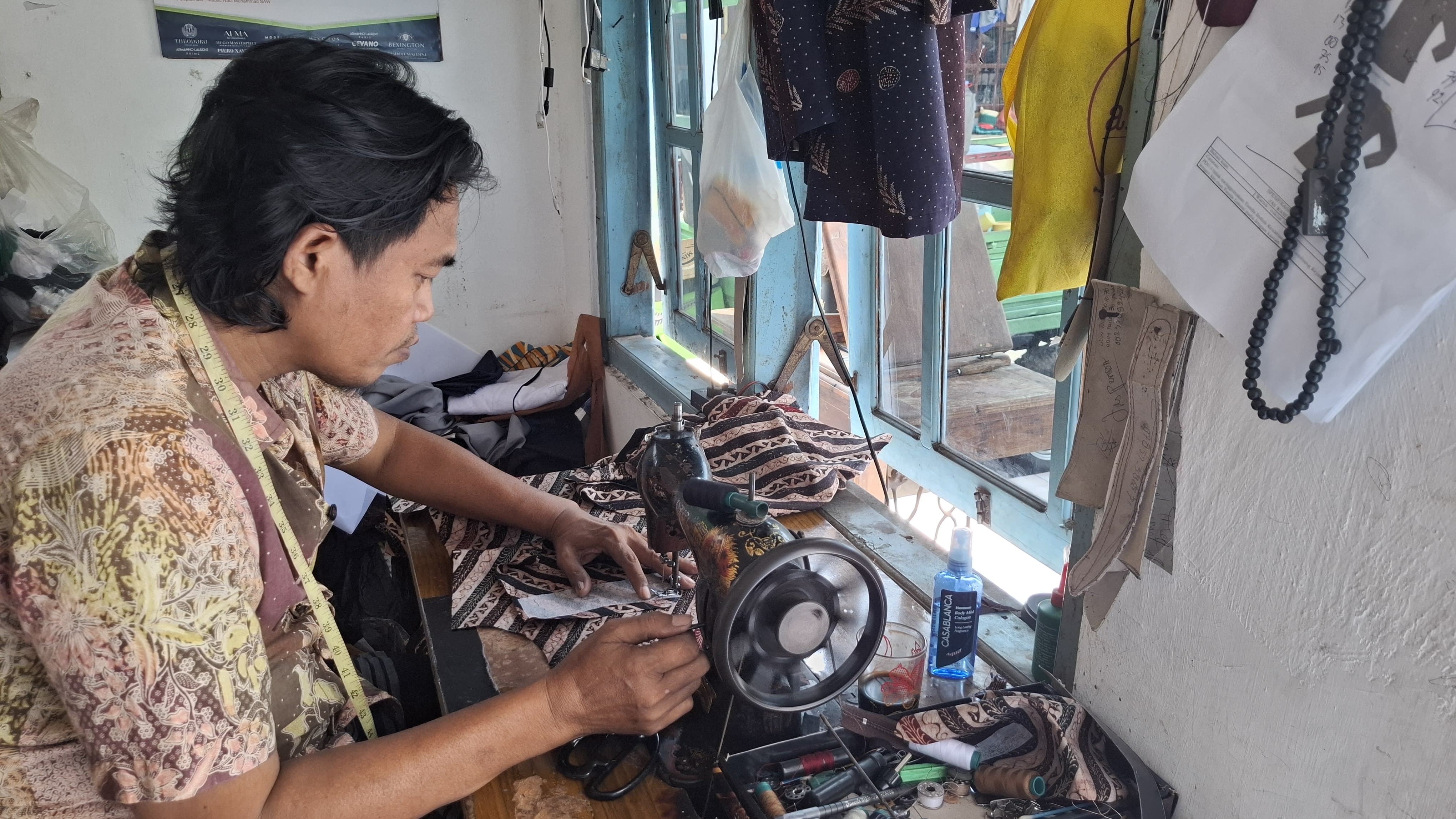 PELAKU IKM: Syaifiudin menjahit baju pesanan pelanggan di Kelurahan Kemayoran, Kecamatan Kota Bangkalan, kemarin (1/5). (IMAMUIDN/JPRM)