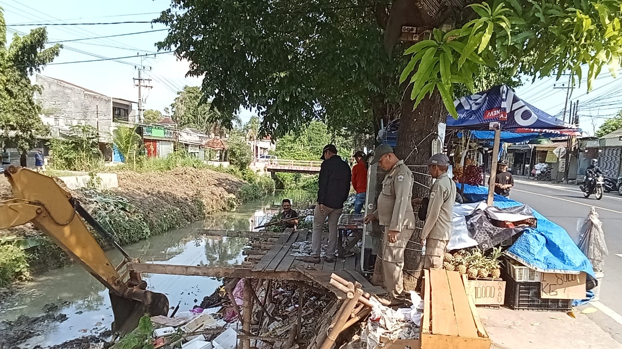 HARUS TERTIB: Personel Satpol PP Bangkalan membongkar lapak PKL di tepi DAS Tunjung, Kecamatan Burneh, kemarin. (SATPOL PP UNTUK JPRM)