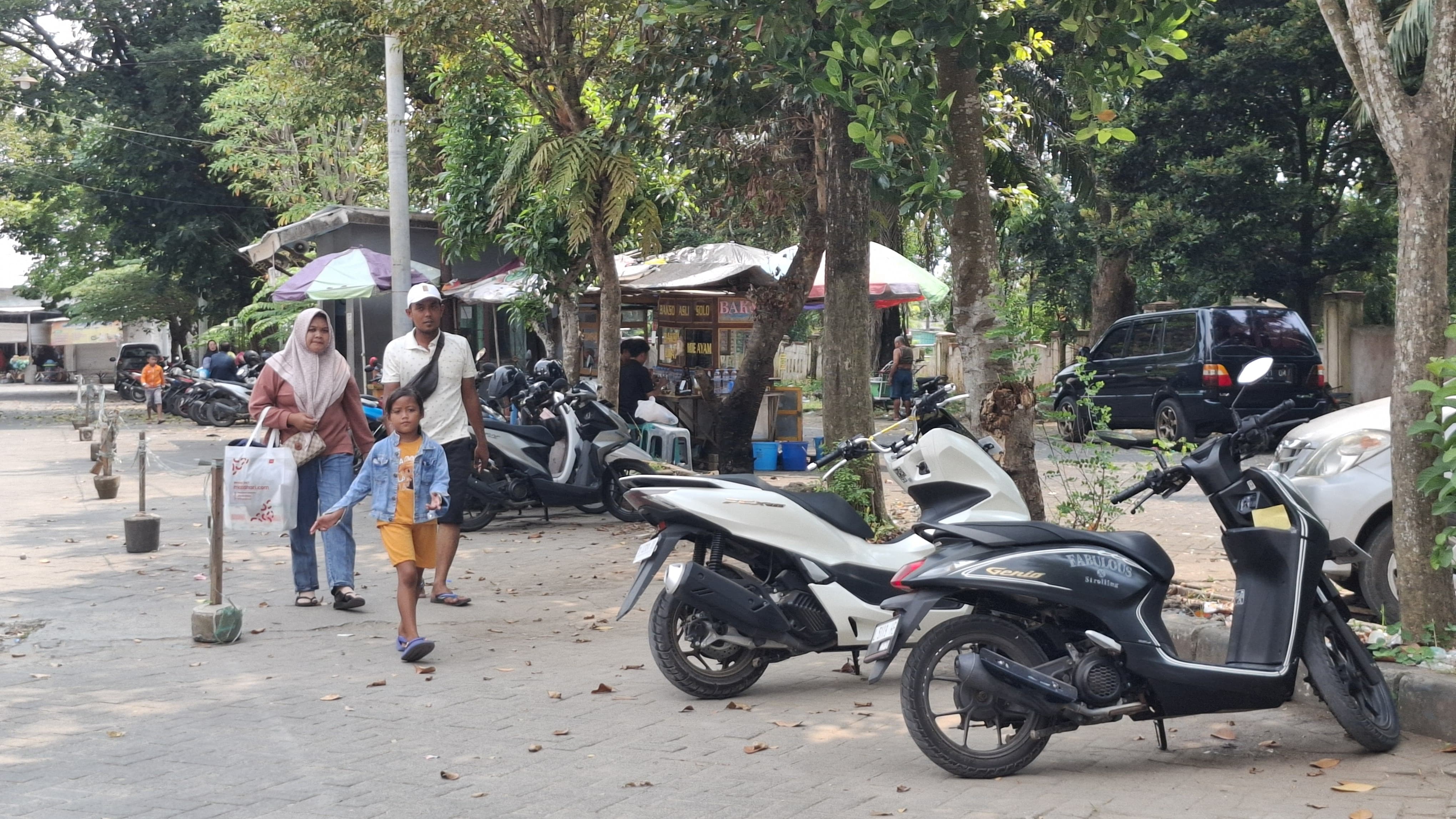 SUMBER PAD: Warga sedang berjalan di area parkir sepeda motor di Pasar KLD Bangkalan kemarin. (IMAMUDIN/JPRM)
