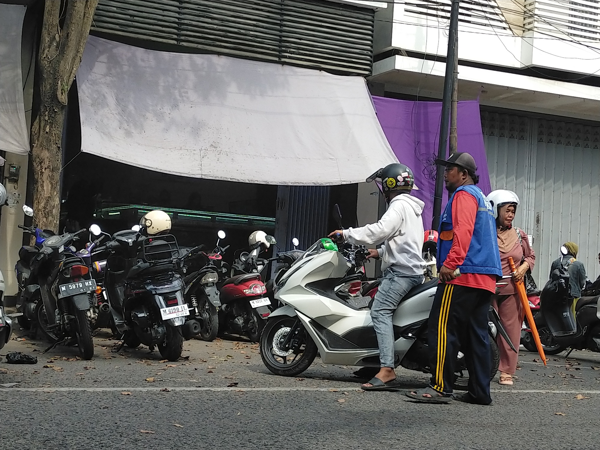 SERING TAK TERTIB: Juru parkir di Jalan Panglima Sudirman tampak mengawal pengendara sepeda motor, Kamis (8/5). (VIVIN AGUSRTIN HARTONO/JPRM)