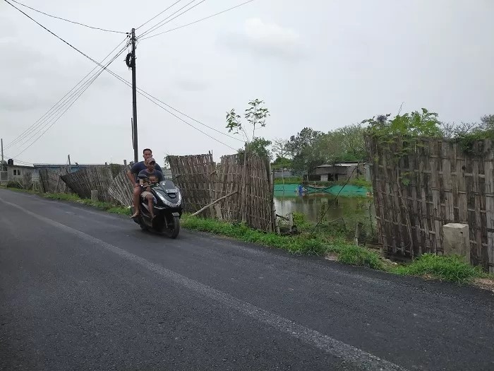 PRODUKTIF: Warga melintas di area tambak Jalan Maritim, Socah, Bangkalan, Selasa (28/11/23). (VIVIN AGUSTIN HARTONO/JPRM)