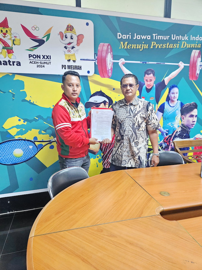 KECEWA: Pengurus KONI Bangkalan Hasan (jaket merah) menyerahkan berkas protes kepada panitia, Selasa (24/6). (KONI BANGKALAN UNTUK JPRM)