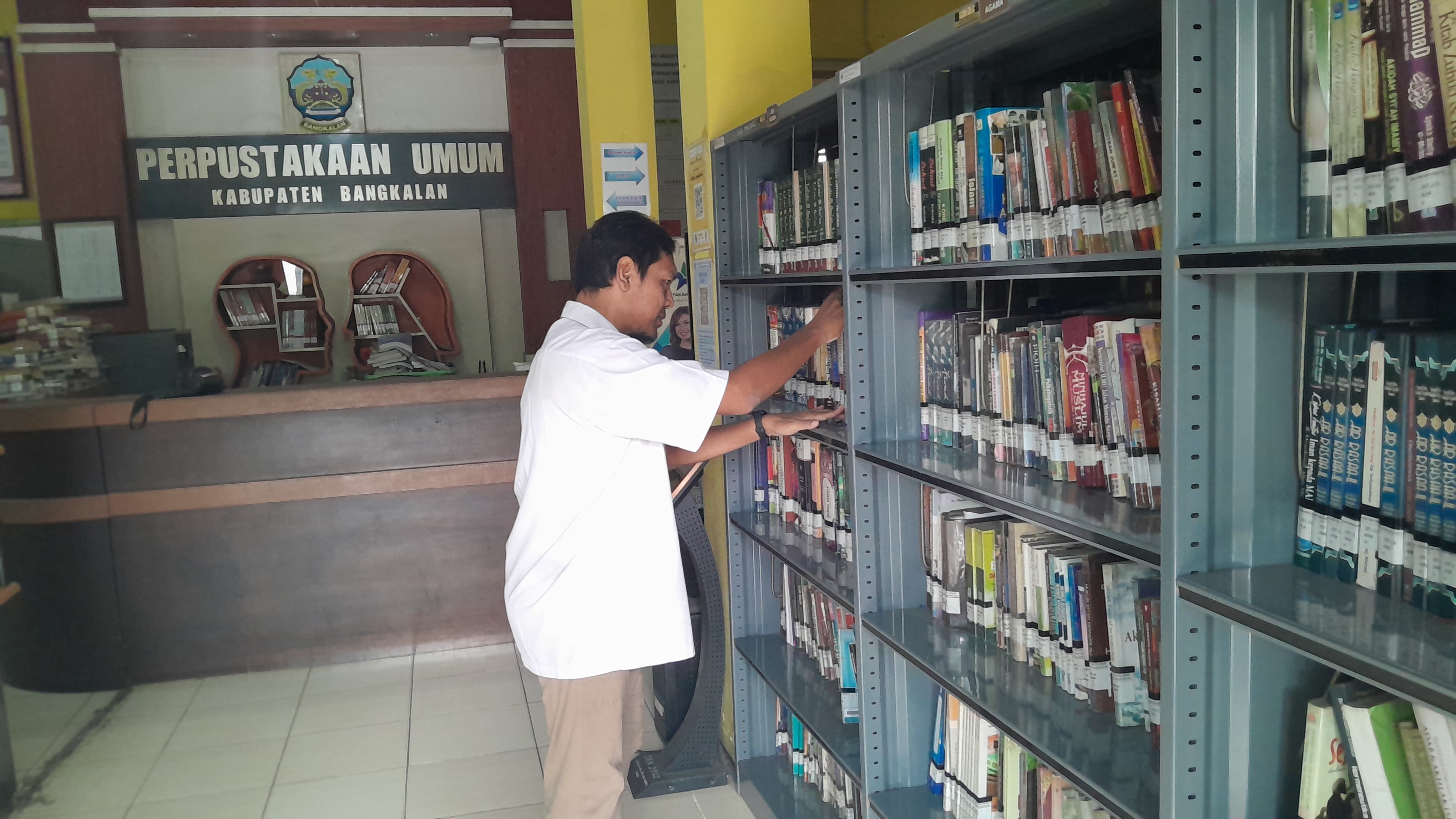 JENDELA DUNIA: Petugas Perpusda Bangkalan sedang merapikan koleksi buku Rabu (25/6). (M. KHOLIL RAMLI/JPRM)