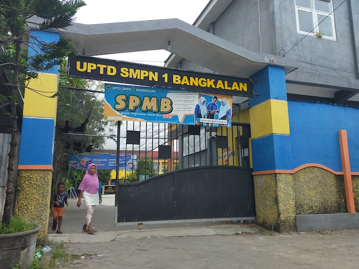 LENGANG: Warga dan seorang bocah keluar dari pintu masuk SMPN 1 Bangkalan yang terletak di Jalan Letnan Ramli Nomor 1B Bangkalan Kamis (26/6). (VIVIN AGUSTIN HARTONO/JPRM)
