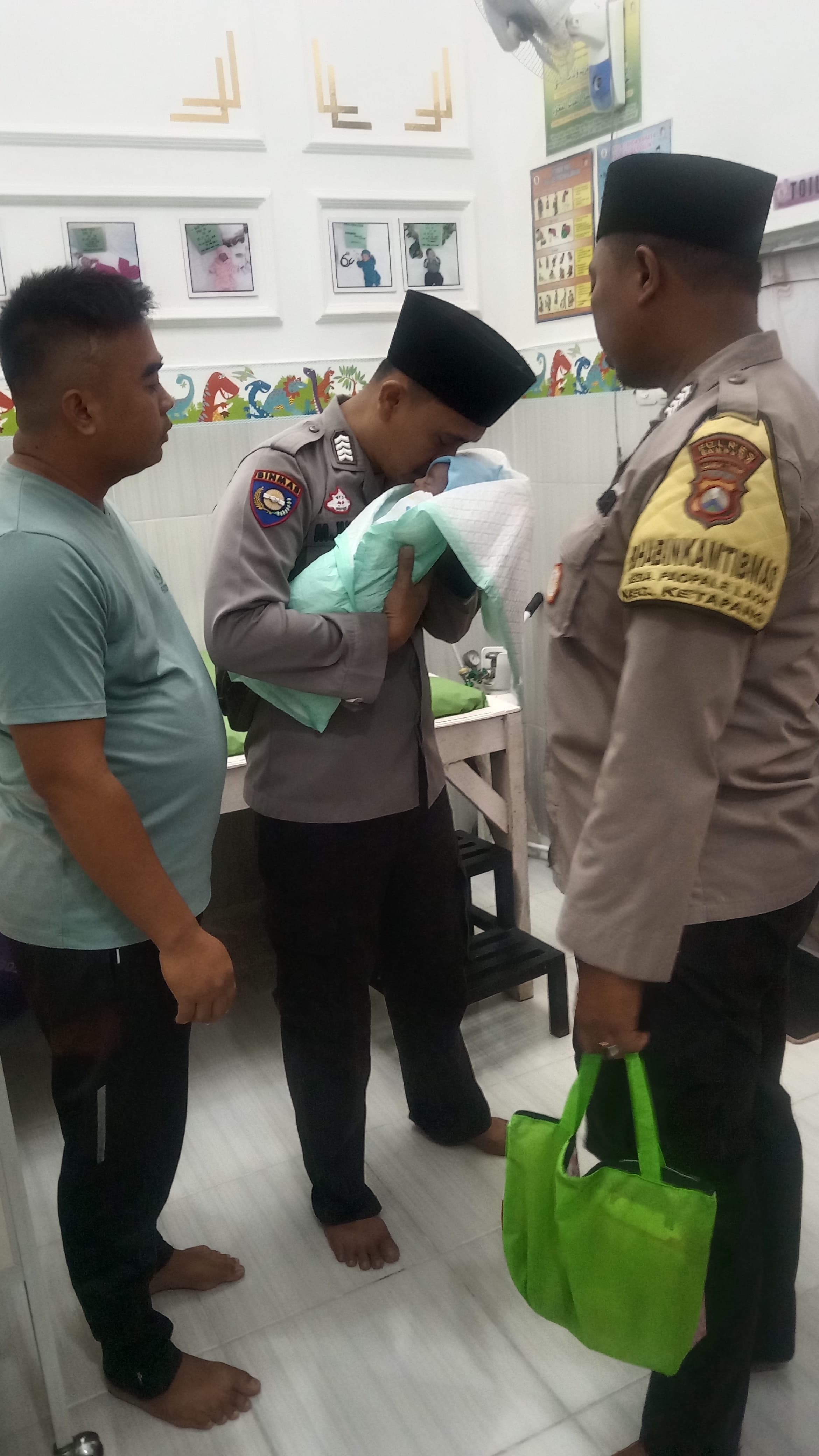 AJAGA SAMPANG: Anggota Polsek Ketapang mengumandangkan adzan di telinga bayi yang ditemukan di Desa Ketapang Barat, Kecamatan Ketapang, Kamis (26/6) malam. (HUMAS POLRES UNTUK JPRM)