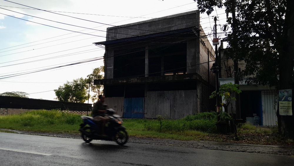 TERBENGKALAI: Pengendara roda dua melintas di sekitar bangunan lantai dua di Jalan Soekarno Hatta, Desa Bilaporah, Kecamatan Socah, Bangkalan, kemarin.