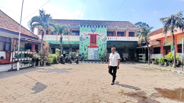 SARANA PENDIDIKAN: Seorang guru melintas di lingkungan SDN Mlajah 2, Bangkalan, Rabu (2/7).