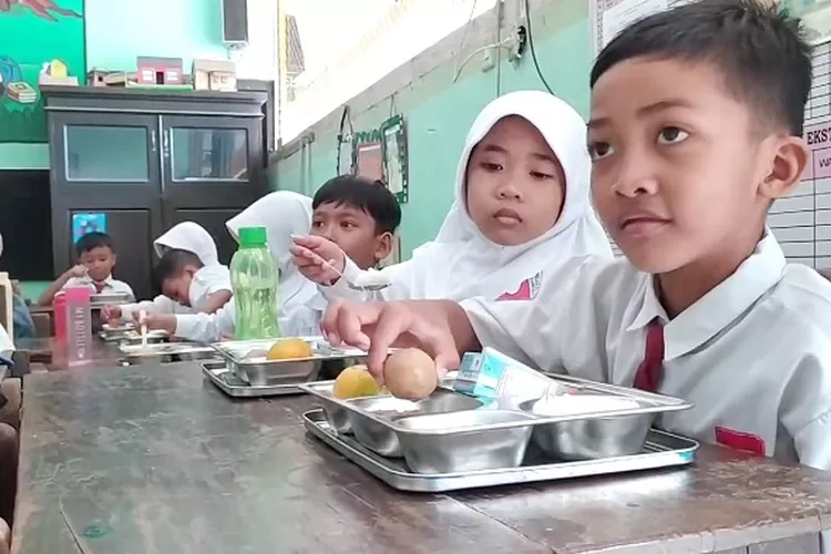 PEMENUHAN GIZI: Siswa menikmati menu makan siang gratis di SDN Pandian 1, Kecamatan Kota Sumenep, Senin (13/1).