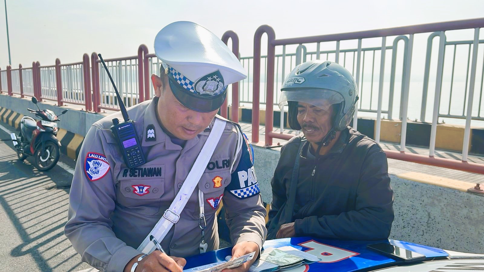 F-OPS BKL lil (2) POLRES BANGKALAN UNTUK JPRM DITILANG: Anggota Satlantas Polres Bangkalan menindak pelanggar lalu lintas di Jembatan Suramadu, Jumat (18/7).