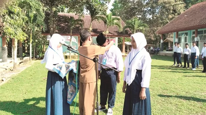 MENDIDIK SEPENUH HATI: Kepala UPTD SMPN 3 Geger Wahid Wahjudi memasang kartu peserta MPLS kepada siswa baru. )