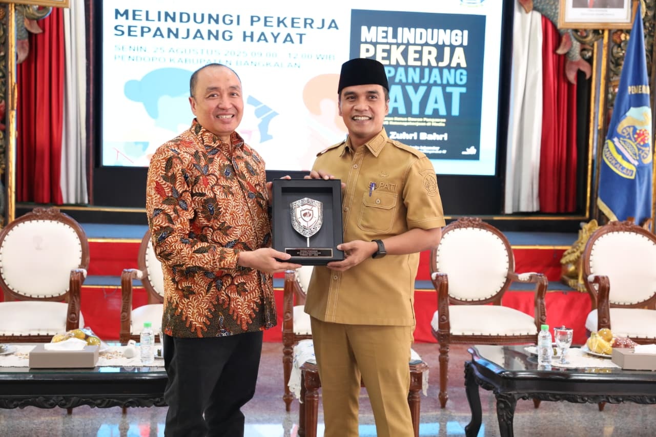 KENANG-KENANGAN: Ketua Dewan Pengawas BPJS Ketenagakerjaan M. Zuhri Bahri menyerahkan cenderamata kepada Bupati Lukman Hakim di Pendopo Agung Bangkalan, Senin (25/8).
