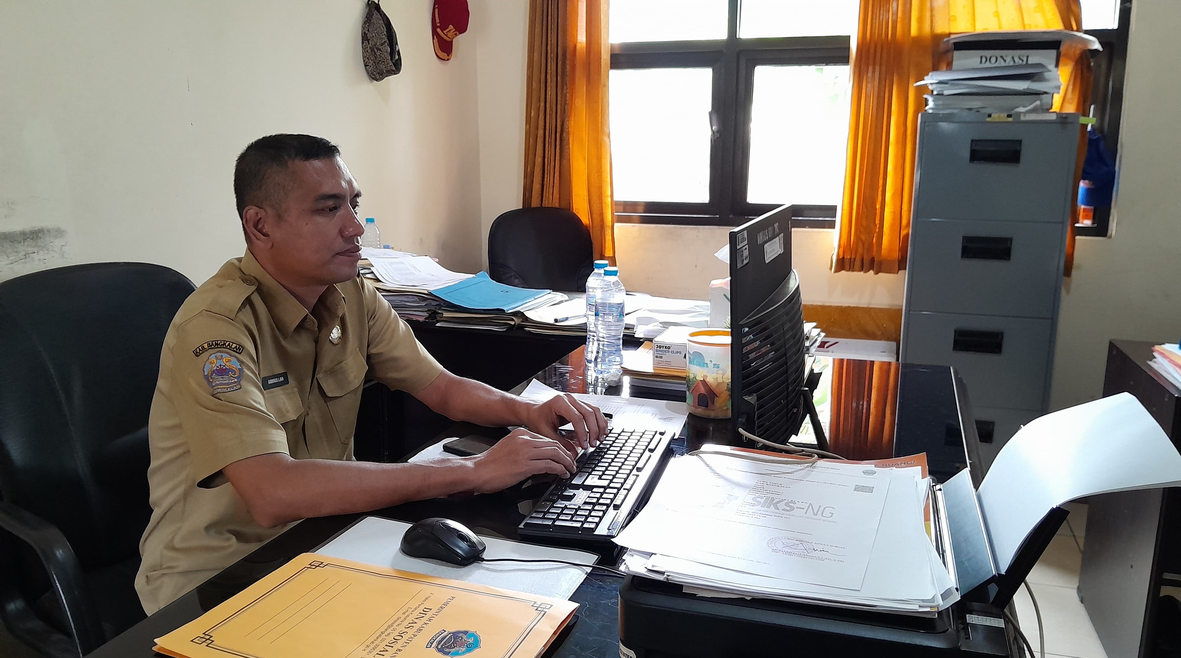 TUNJUKKAN DATA: Kepala Bidang Linjamsos Dinsos Bangkalan Mohammad Aminullah saat ditemui di ruang kerjanya, Selasa (2/9).