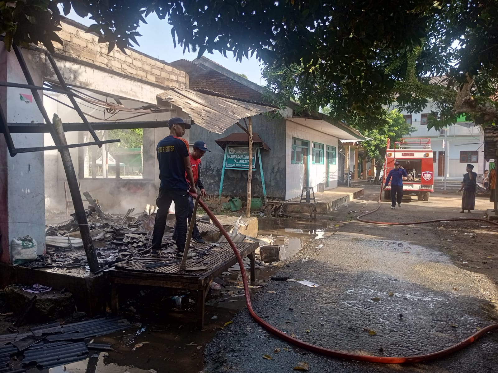 BERHASIL DIPADAMKAN: Petugas pemadam kebakaran sedang memadamkan toko terbakar di Desa Keleyan, Kecamatan Socah, Selasa (22/11).