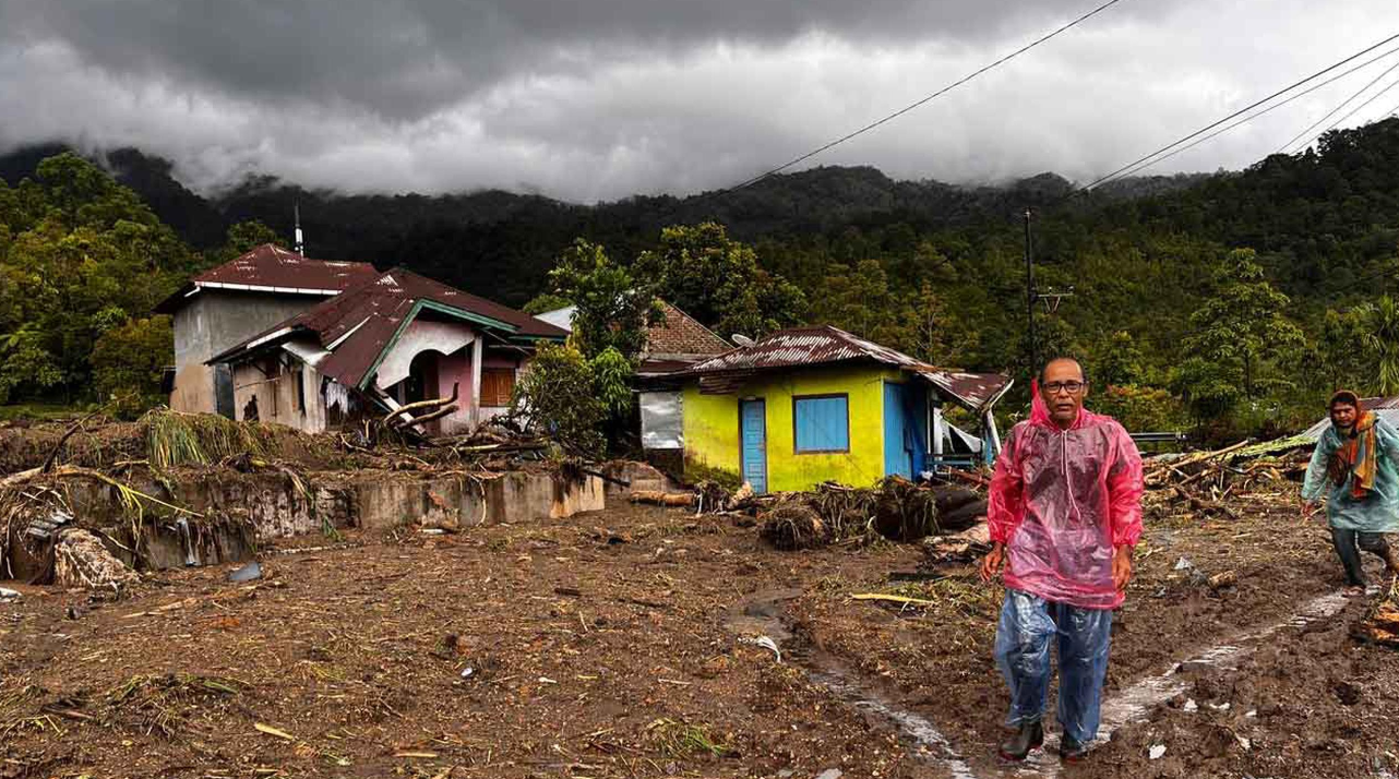Warga berjalan melewati rumah-rumah yang rusak di sebuah desa yang terdampak banjir di Malalak, Sumatera Barat, Jumat 28 November 2025. (AP Photo/Ade Yuandha)