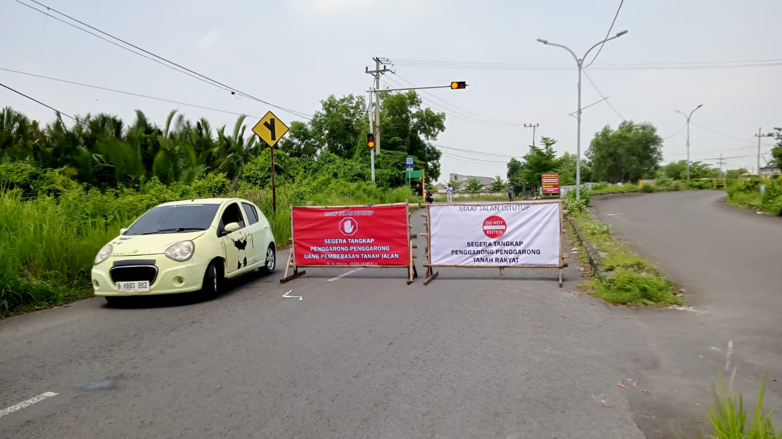 Plang protes pemilik lahan berada di tengah Jalan ring road barat atau Kinibalu.