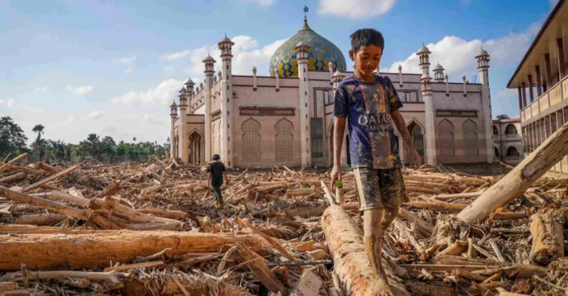 Seorang bocah berjalan meniti kayu-kayu yang memenuhi area Pondok Pesantren Darul Mukhlishin pascabanjir bandang. (ANTARA FOTO/Erlangga Bregas Prakoso)