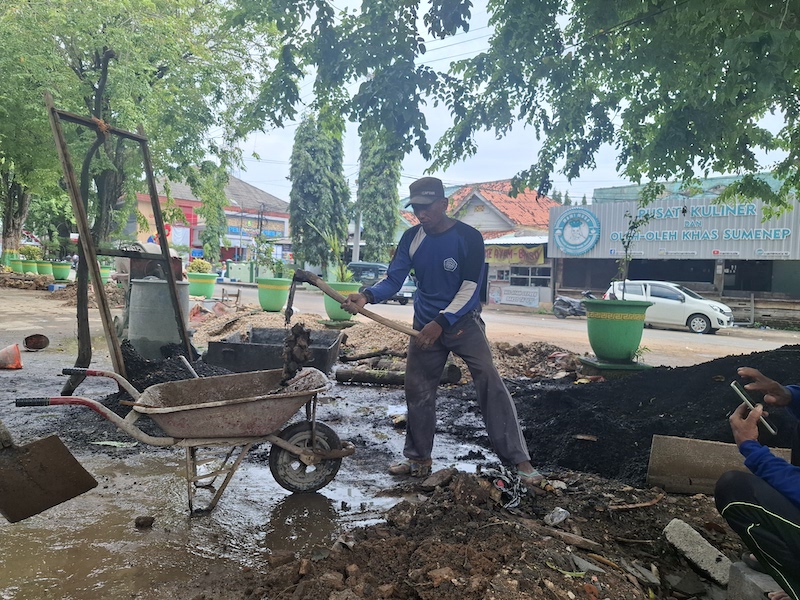 MOLOR: Pekerja tengah membersihkan material proyek di Taman Bunga Pottre Koneng Sumenep, Senin (22/12).&nbsp;