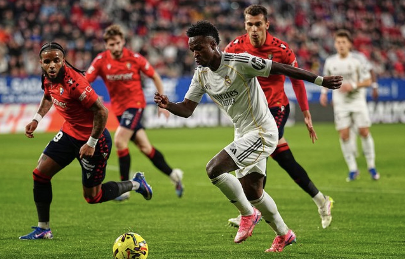 Vinicius Junior berebut bola dengan Valentin Rosier dalam laga Liga Spanyol antara Osasuna vs Real Madrid di Estadio El Sadar, 22 Februari 2026 (c) AP Photo/Miguel Oses
