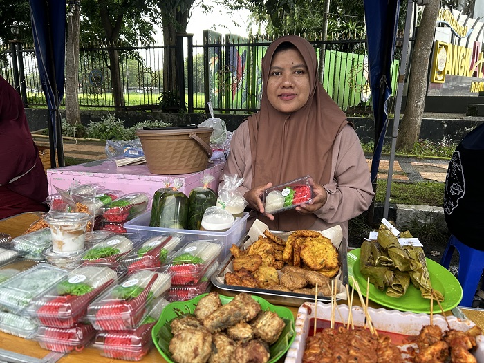 KUDAPAN: Sufiya menunjukkan menu favorit yang sering dicari pemburu takjil di stan 3 Bazar Takjil Ramadan, Bangkalan, Selasa (3/3).