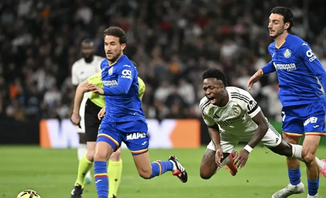 Bek Getafe CF Juan Iglesias (kanan), berebut bola dengan penyerang Real Madrid Vin&iacute;cius J&uacute;nior (tengah) dalam pertandingan Liga Spanyol di Santiago Bernab&eacute;u, 2 Maret 2026. (AFP)